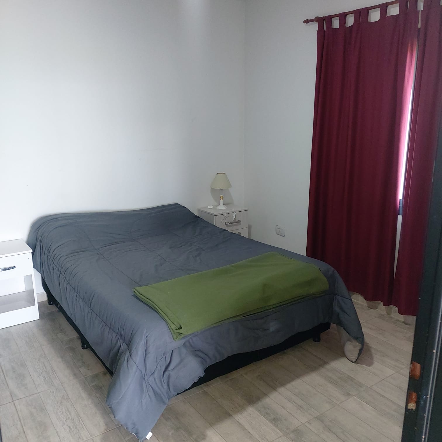 Dormitorio con cama matrimonial y ropa de cama gris y verde