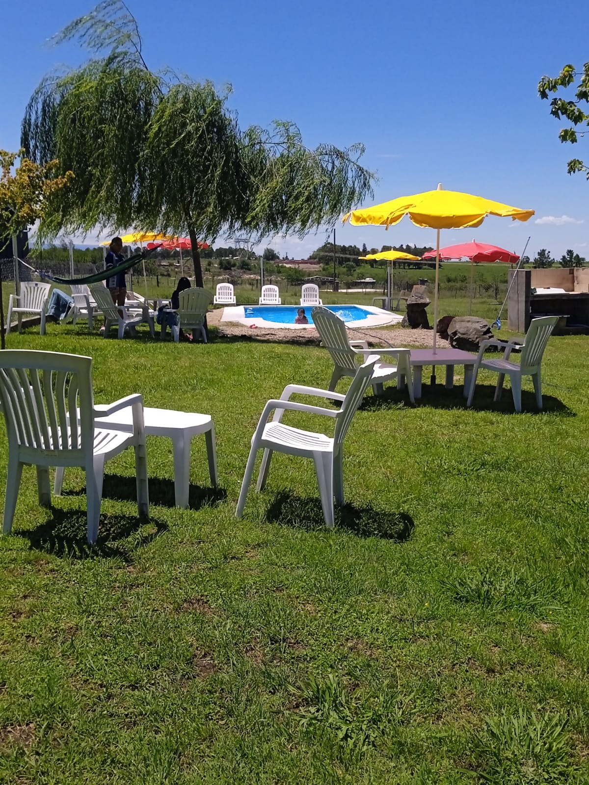 Pileta de Cabañas Leon en un día soleado con sombrillas de colores